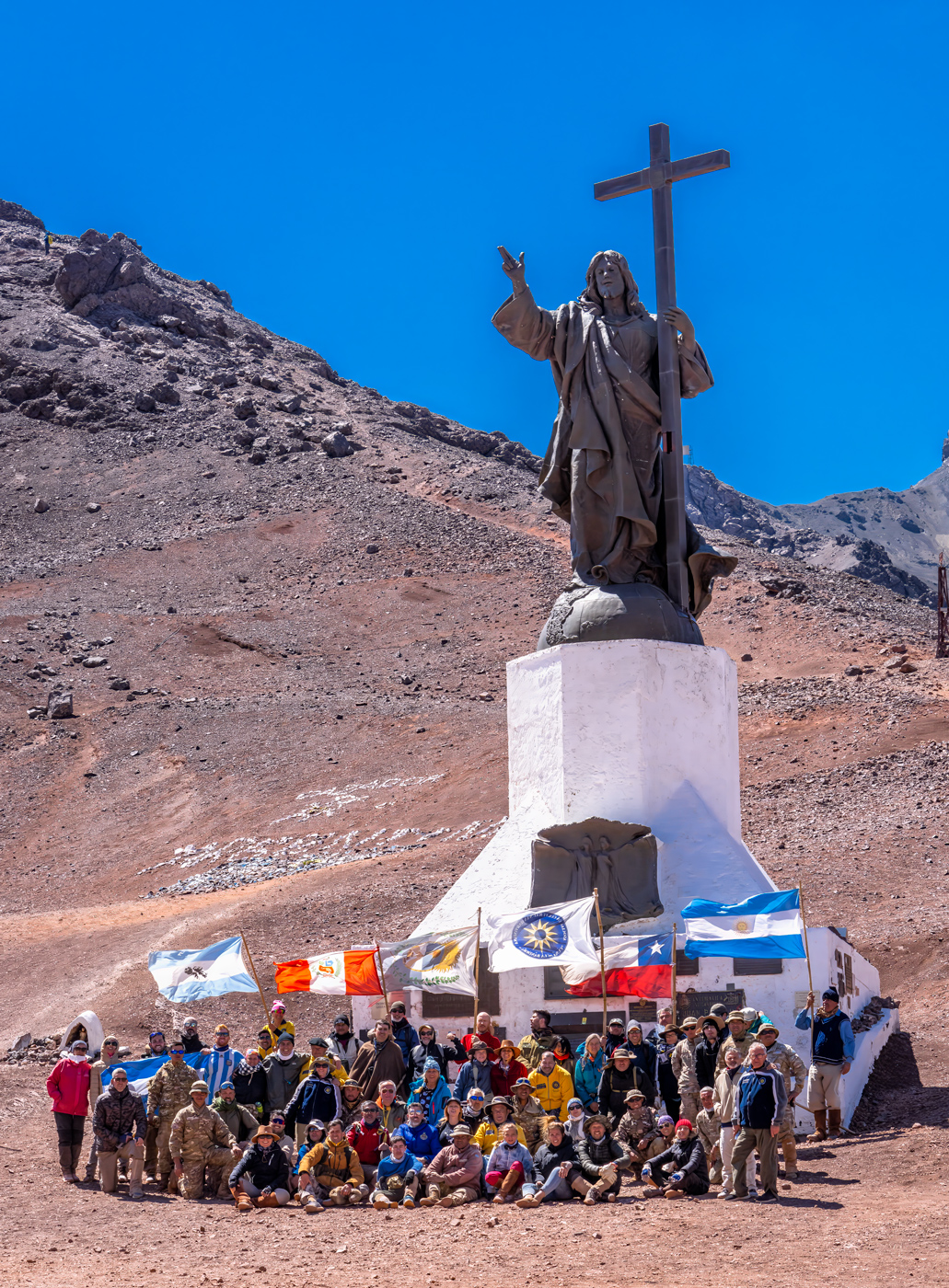 Grupo en el monumento Cristo Redentor con banderas de Argentina, Chile y otras naciones