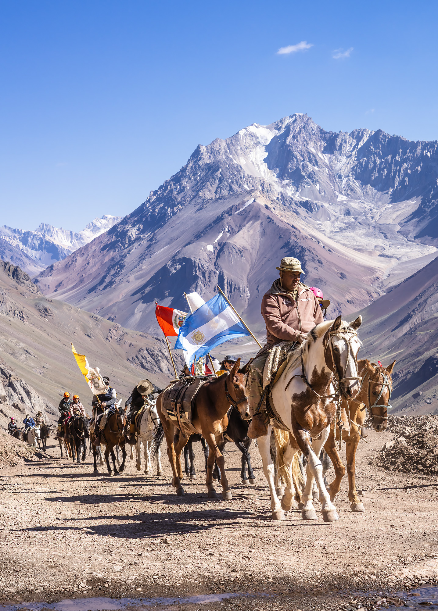 Jinetes con banderas atravesando la cordillera de los Andes con picos nevados