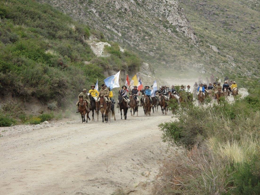Jinetes con banderas argentinas en camino polvoriento