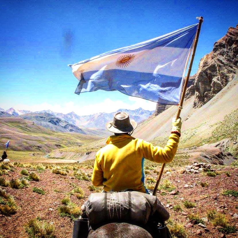Jinete con bandera argentina alzada en el paisaje andino
